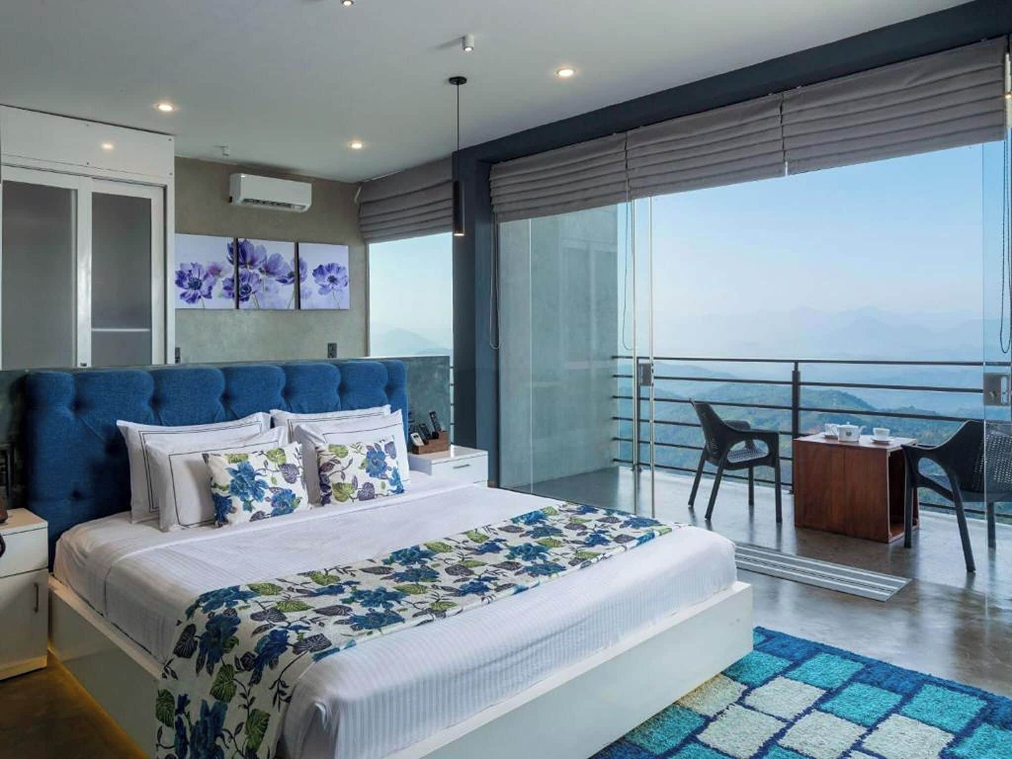 Un dormitorio moderno con una cama grande, un balcón con vistas y una zona de comedor.