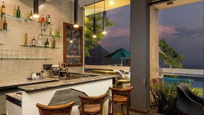 Uma área de bar com balcão, banquetas e prateleiras cheias de garrafas.