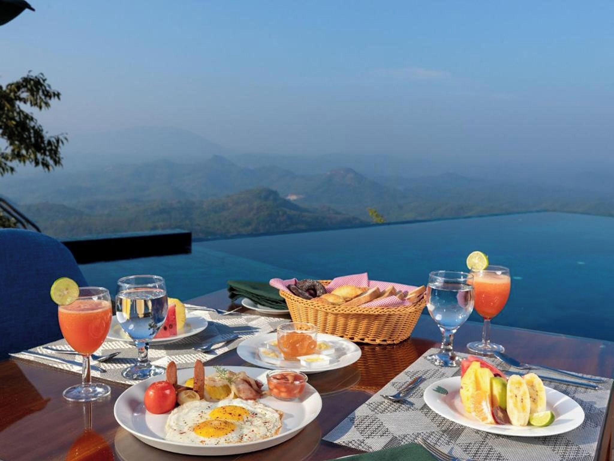 A table set with breakfast items, including eggs, toast, and fruit, overlooking a mountainous landscape.