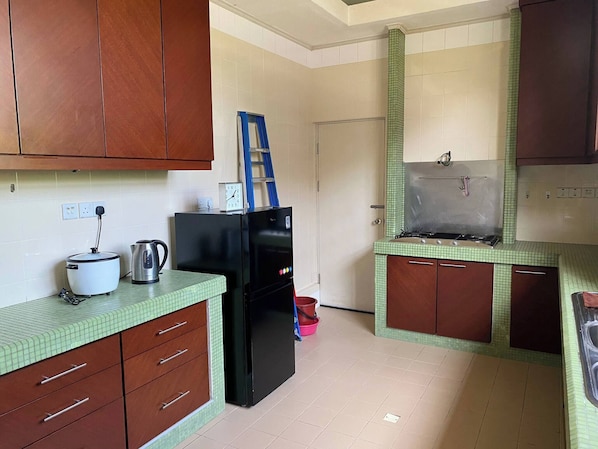 Una cocina con refrigerador, estufa y un reloj encima. Hay armarios y un lavamanos.