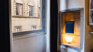 Une pièce dotée d’une grande fenêtre, d’une étagère fixée au mur sur laquelle se trouve un globe terrestre, et d’un luminaire fixé au mur.