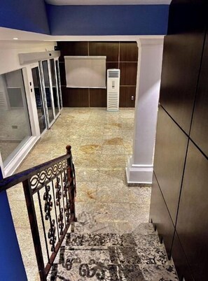 A hallway with a tiled floor, a white air conditioning unit, and a white wall-mounted object. - M3 Suites (Port Harcourt)