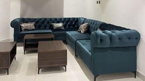 En moderne stue med en hjørnesofa, to sofaborde og indbygget loftbelysning.