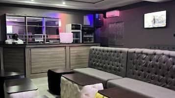 A modern lounge area with a sofa, cushioned ottomans, and a bar counter.
