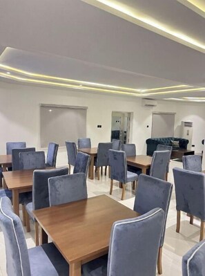 A modern dining area with multiple tables and chairs, a sofa, and a coffee machine. - M3 Suites (Port Harcourt)