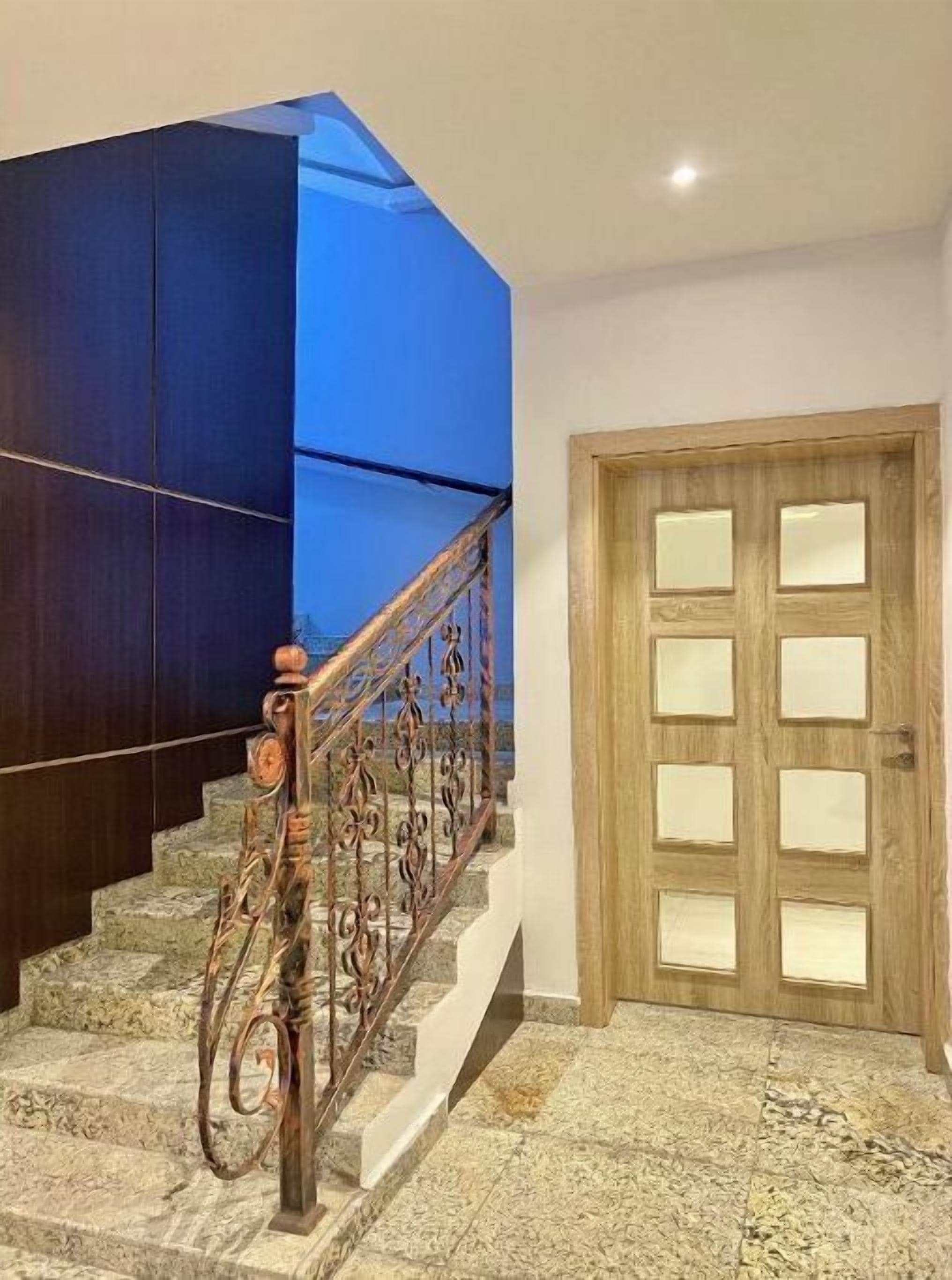 Una escalera con barandilla de madera y una pared azul decorativa.