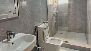 Et badeværelse med vask, toilet og bruseniche.