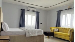 Et hotelværelse med en seng, en sofa, et lille bord og en aircondition.