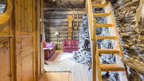 A log cabin interior with a wooden staircase, a red leather sofa, and a stone wall. - Luostonseita 2 by Interhome (Sodankylä)