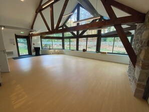 Ein geräumiges Zimmer mit hohen Decken, großen Fenstern und Holzboden.