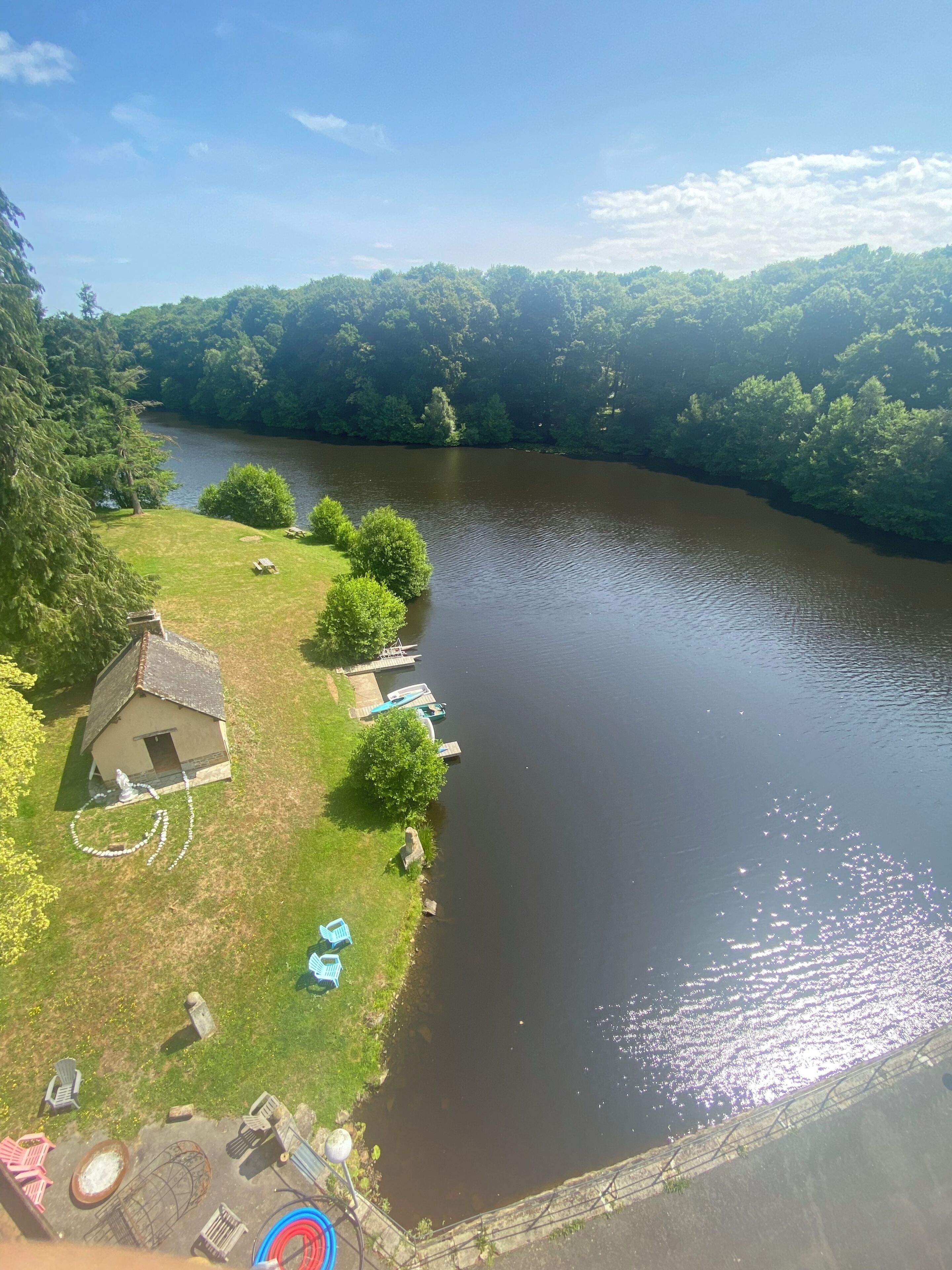 A riverside view with a small house, boats, and outdoor seating.
