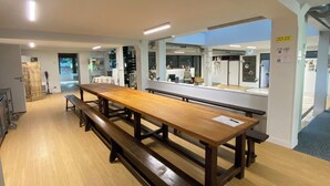 A dining area with a long wooden table and benches, a mirror on the wall, and a door with a sign. - Large vacation rental for 15 people with a private pond • 45 minutes from Mont Saint-Michel (Landéan)