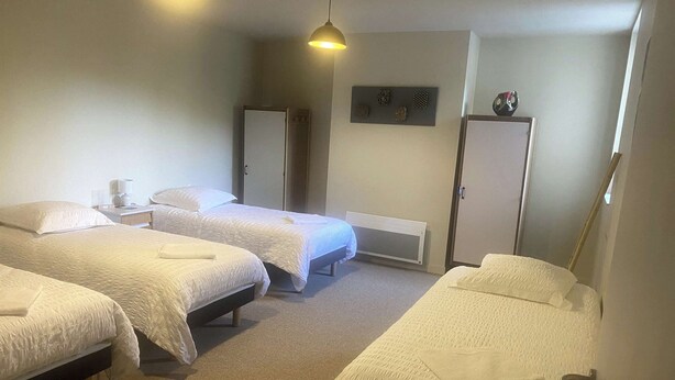 A hotel room with three beds, a bedside table with a lamp, a wardrobe, and a wall-mounted decoration. - Large vacation rental for 15 people with a private pond • 45 minutes from Mont Saint-Michel (Landéan)