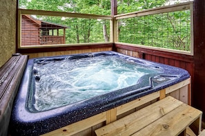A hot tub with a wooden bench, surrounded by wooden walls and a window with a view of trees. - Spacious Cabin Retreat with Hot Tub & Games near Dollywood in Pigeon Forge, TN (Pigeon Forge)