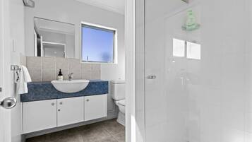 A modern bathroom with a white sink, blue countertop, and a glass shower enclosure.