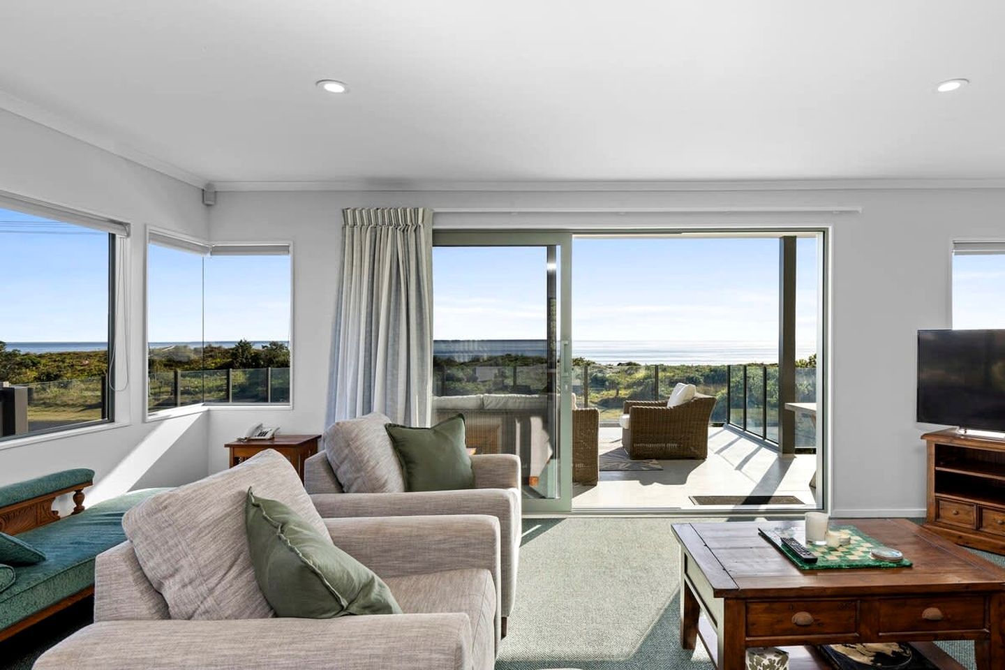 A spacious living area with a balcony, large windows, and a flat-screen TV.