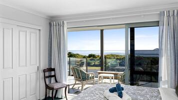 Une chambre d’hôtel avec un lit, une chaise, une petite table et un balcon donnant sur la mer.