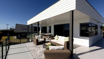 A modern house with a covered patio, outdoor furniture, and a clear view of the surrounding area.