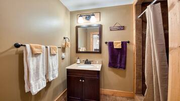 Ein Badezimmer mit Waschbecken, Spiegel und Handtüchern an Handtuchhaltern.