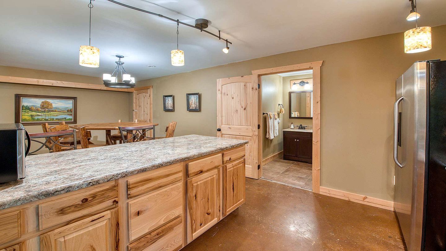 A kitchen with wooden cabinets, granite countertops, and a stainless steel refrigerator.