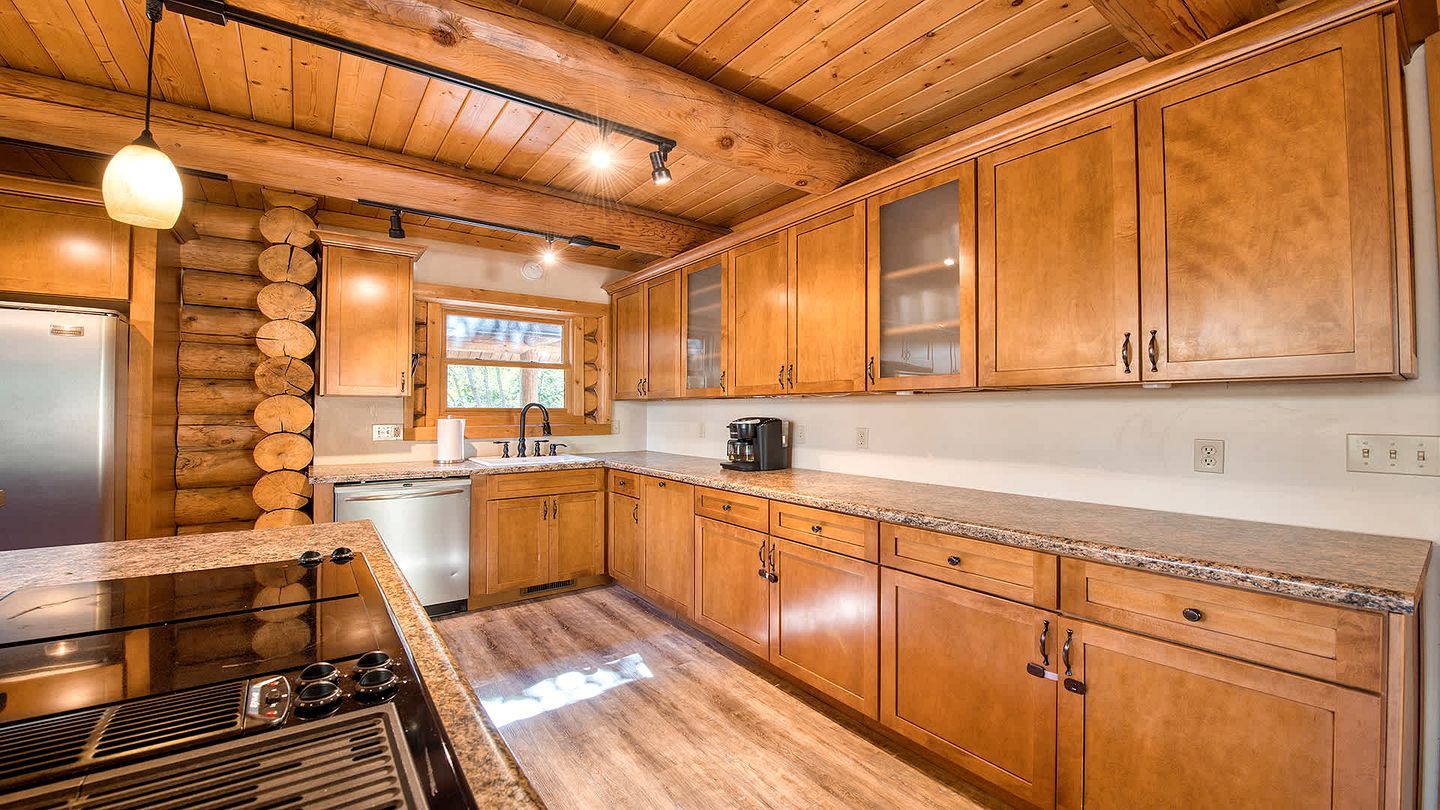 A kitchen with wooden cabinets, a stainless steel refrigerator, a built-in oven, and a granite countertop.