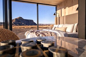 A bedroom with a large window, a bed, and a view of a mountain.