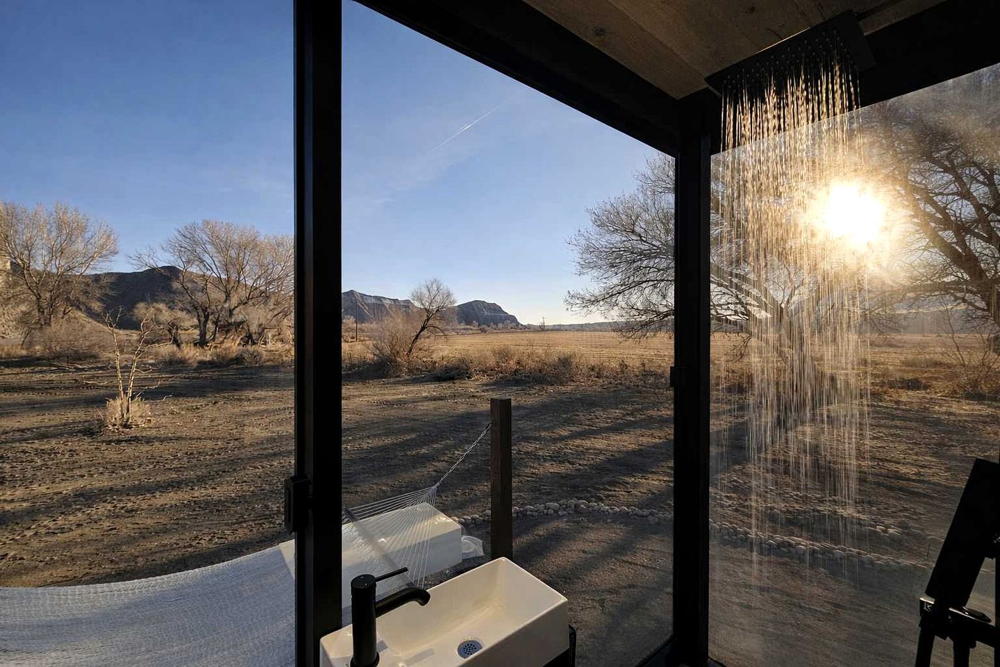 A bathroom with a large window, a sink, and a shower area.