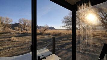 A bathroom with a large window, a sink, and a shower area.