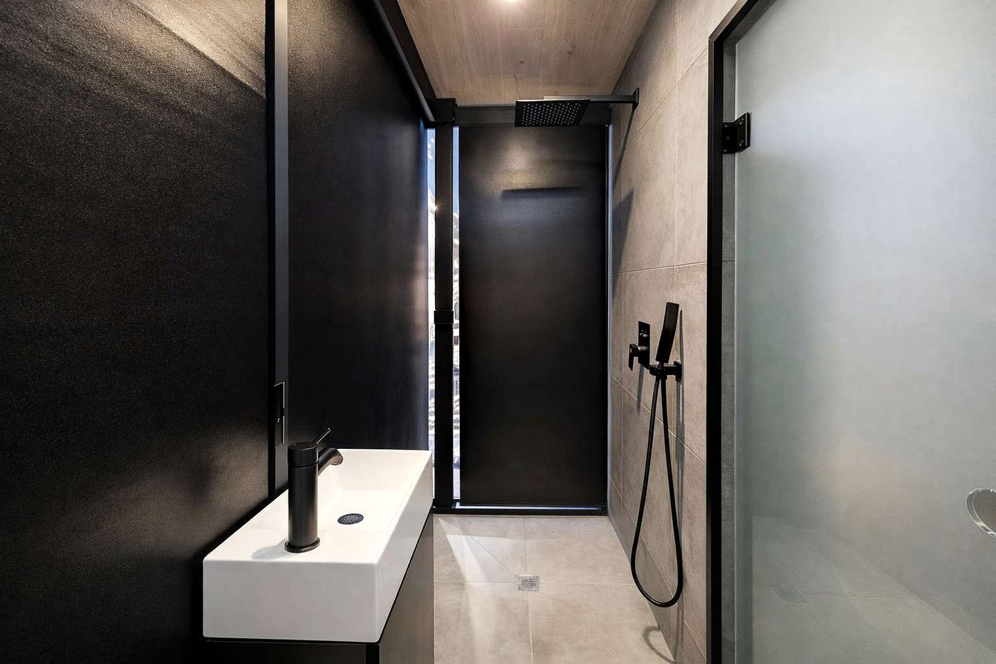 A modern bathroom with a shower, a sink, and a glass partition.