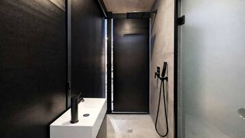 A modern bathroom with a shower, a sink, and a glass partition.