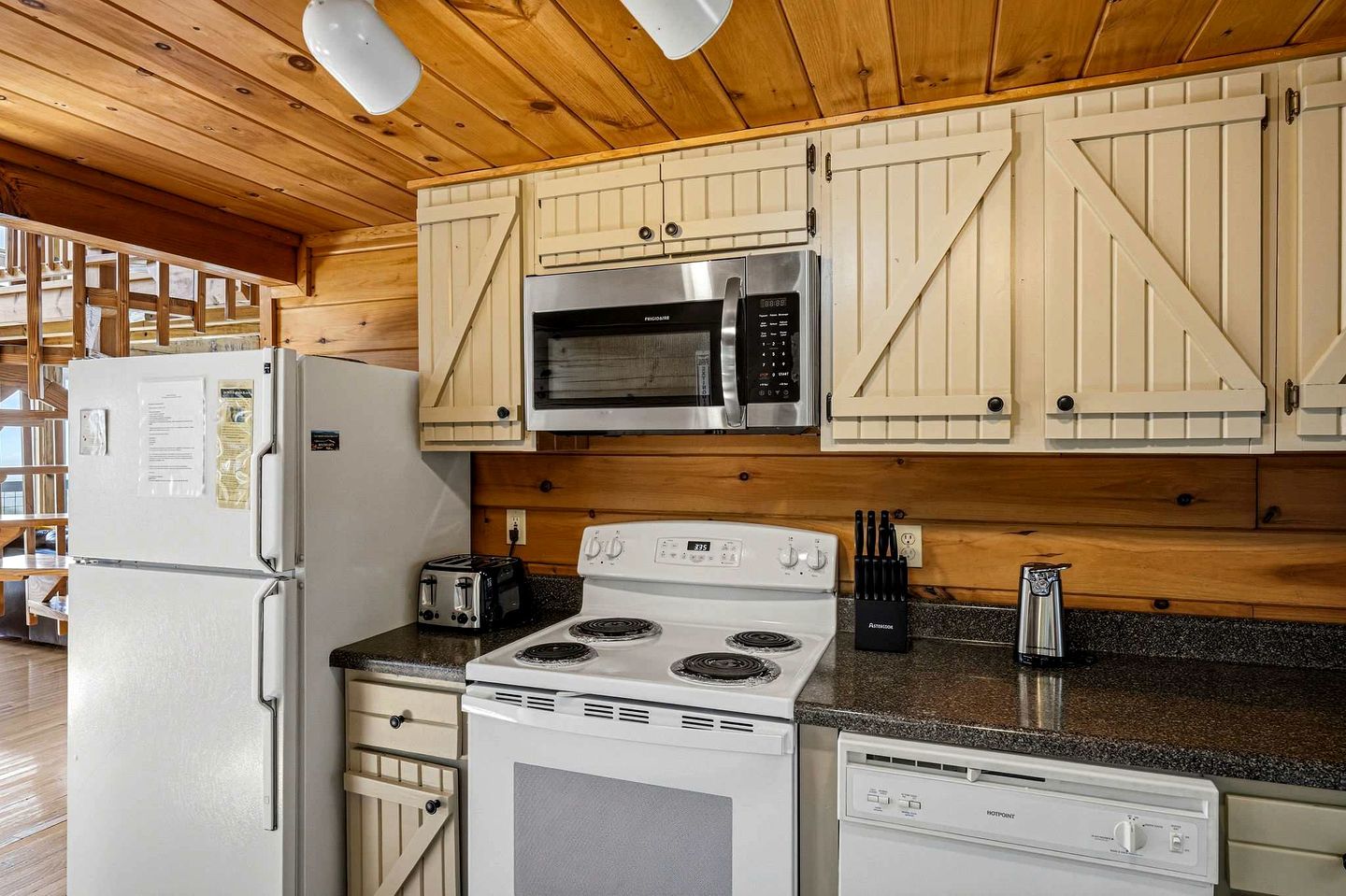 A kitchen with wooden cabinets, a microwave, a stove, and a refrigerator.