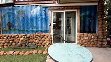 A patio with a round table and chairs, a stone wall, and a mural on the building.