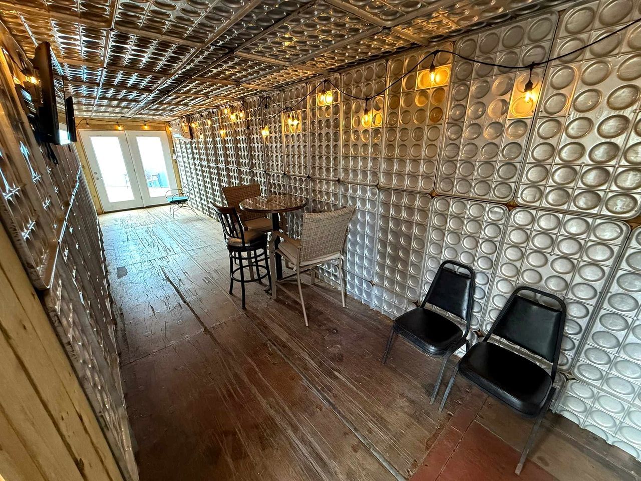 Une pièce dotée d’un plancher en bois, d’une table ronde entourée de chaises et d’un mur orné de motifs circulaires.