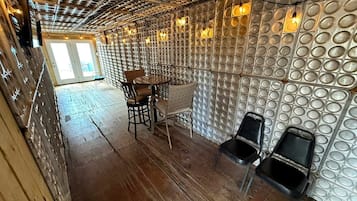 Une pièce dotée d’un plancher en bois, d’une table ronde entourée de chaises et d’un mur orné de motifs circulaires.