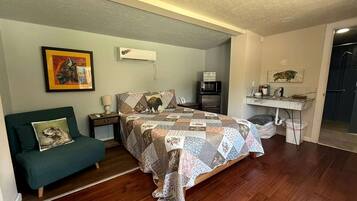 A bedroom with a bed, a desk, a chair, and a painting on the wall.