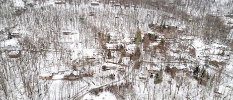 An aerial view of a snow-covered residential area with houses, roads, and a few trees.