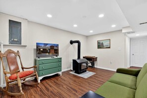 A living room with a fireplace, a television, a rocking chair, and a green sofa. - Spacious Mountain Retreat with Hot Tub & Screened Porch Near Wineries and Appalachian Trail | Harpers Ferry, WV (Harpers Ferry)