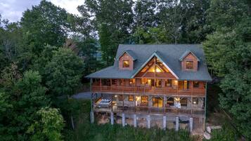 A large wooden cabin with multiple balconies, surrounded by dense forest.