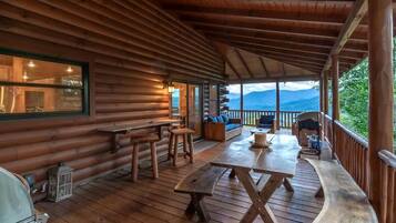 Eine Holzhütte mit überdachter Veranda, Holztischen und -bänken.