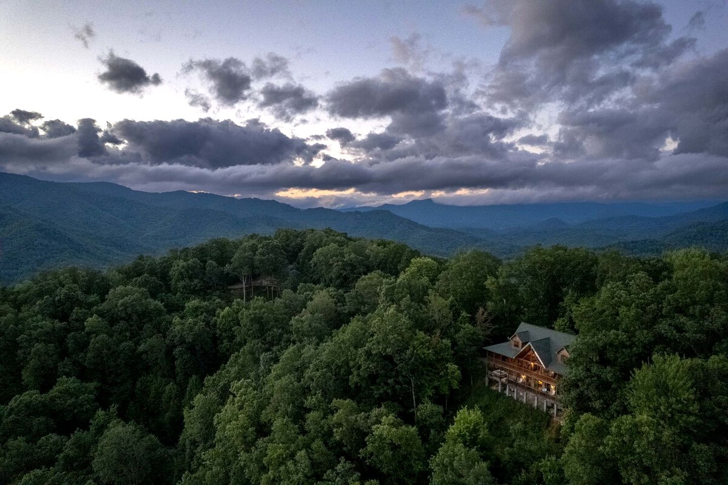 Una cabaña rodeada de un bosque frondoso, con vistas a montañas distantes.