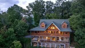 Une grande cabane en bois dotée de nombreux balcons, entourée d’une forêt dense.