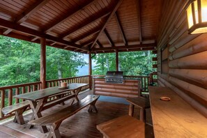 Un espacio al aire libre techado con bancos de madera y una parrilla.