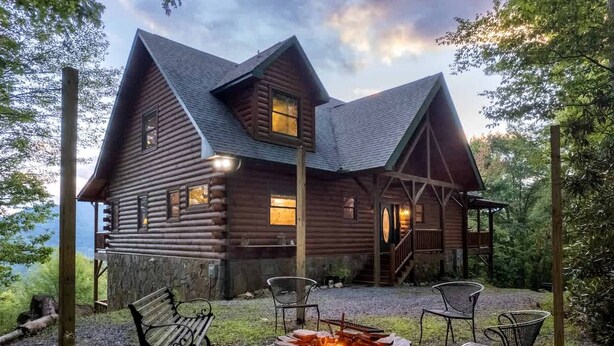 Une cabane en rondins avec un foyer et des sièges d’extérieur.
