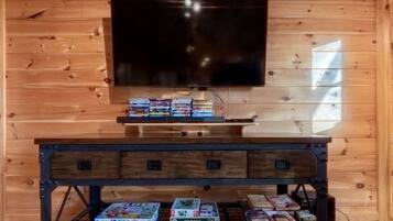 Ein Holzinterieur mit einem Fernseher, der über einer dunklen Holzunterhaltungsecke angebracht ist, in der sich Videospiele und Bücher befinden.