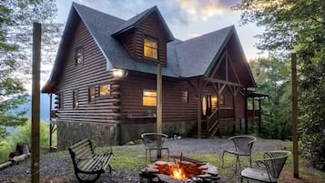Une cabane en rondins avec un foyer et des sièges d’extérieur.