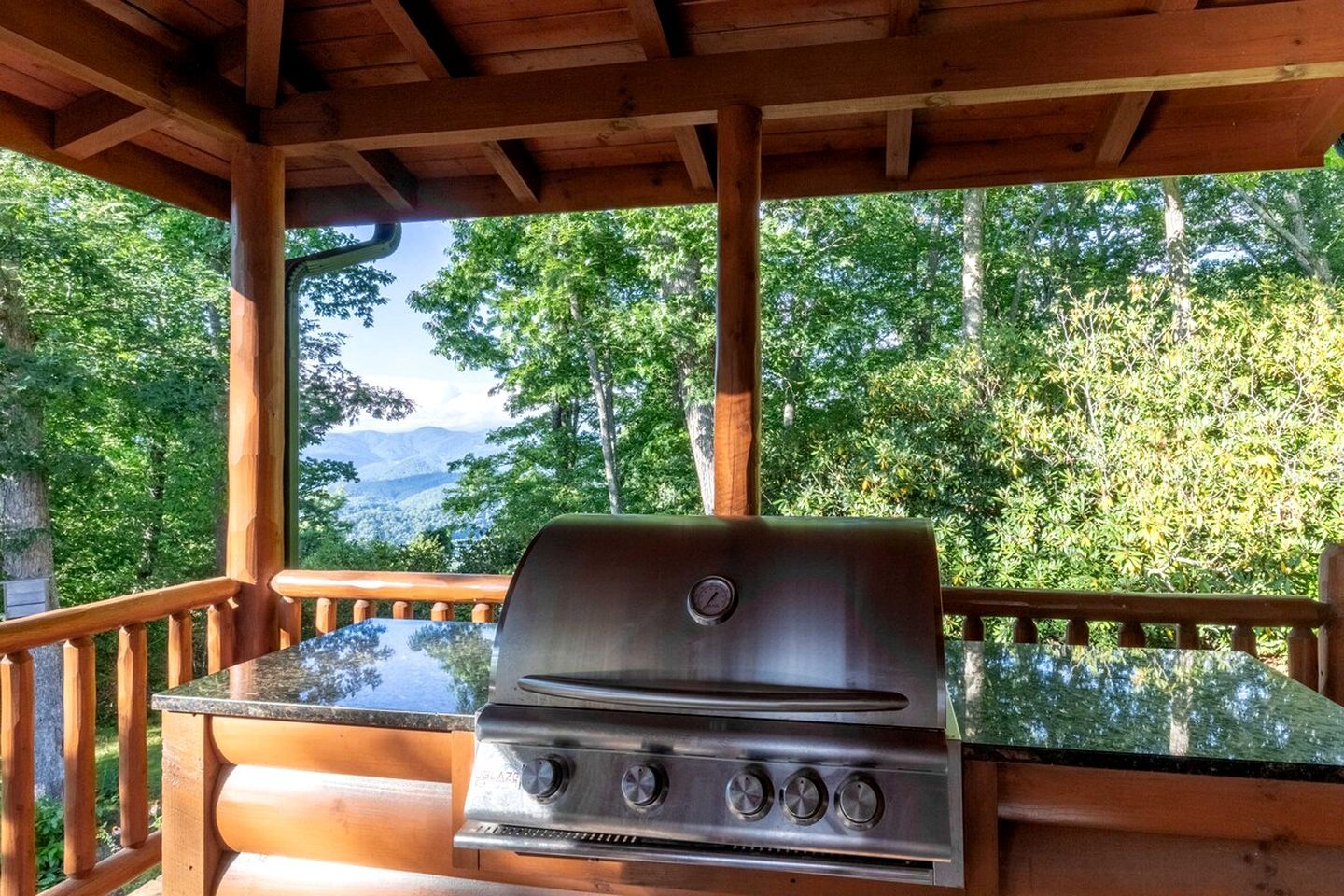 Een barbecue op een terras met uitzicht op een bos en bergen.
