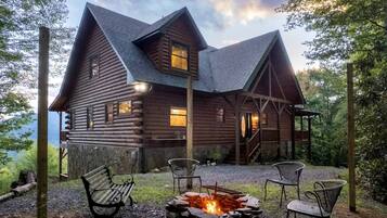 A log cabin with a fire pit and outdoor seating.