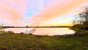 A lakeside view with a grassy foreground and a calm body of water.