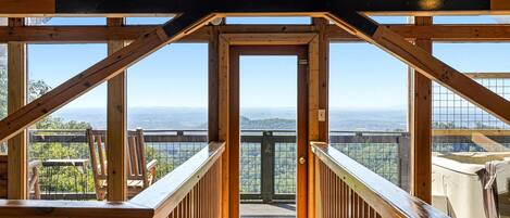 A wooden interior with a view of a mountainous landscape through large windows.