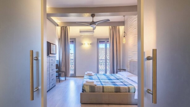 Ein Schlafzimmer mit einem Bett, einem Deckenventilator, einer Kommode und einem Fenster mit Vorhängen.
